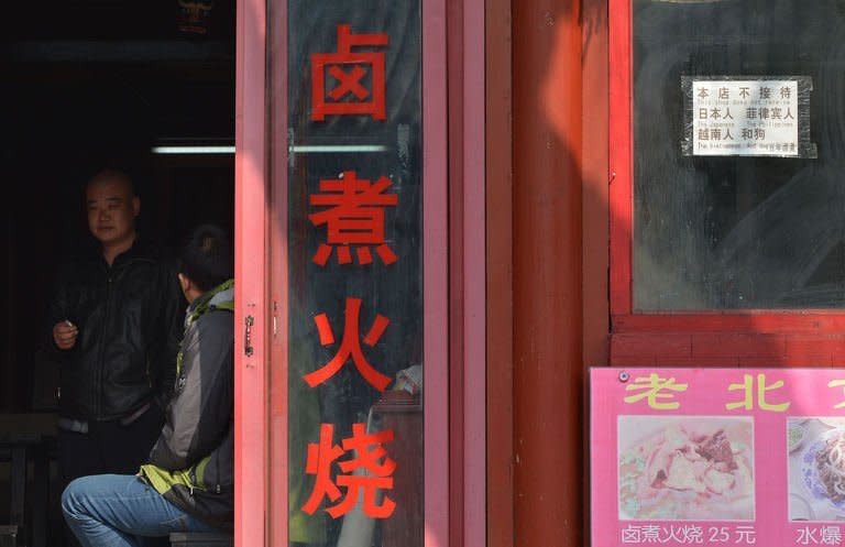 A Chinese man looks out from a restaurant that displays a sign reading, "This shop does not receive the Japanese, The Philippines, The Vietnamese and Dog" in the historic tourist district of Houhai in Beijing on February 26, 2013. China is currently in border disputes with Japan, Vietnam and the Philippines