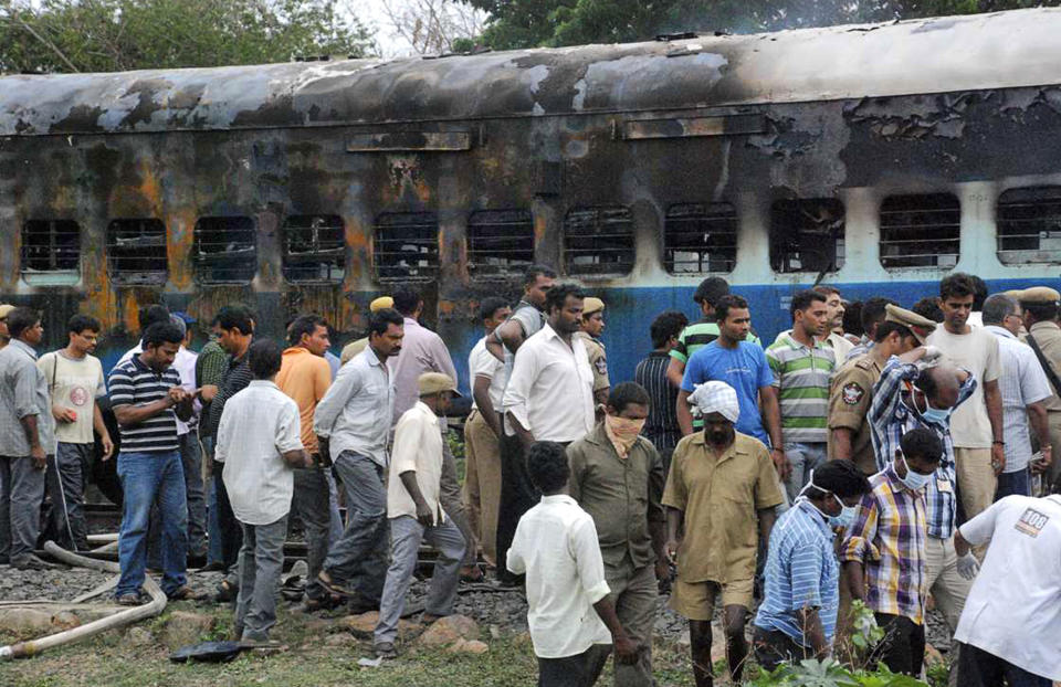 Railway workers and officials inspect the burnt coach of a passenger train at Nellor nearly 500 kilometers (310 miles) south of Hyderabad, India, July 30, 2012. A fire engulfed a passenger car on a moving train in southern India on Monday, killing at least 47 people, officials said.  (AP Photo)