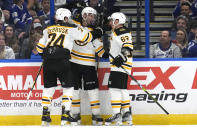 Boston Bruins left wing Brad Marchand (63) celebrates his goal against the Tampa Bay Lightning with center Patrice Bergeron (37) and left wing Jake DeBrusk (74) during the second period of an NHL hockey game Monday, Nov. 21, 2022, in Tampa, Fla. (AP Photo/Chris O'Meara)