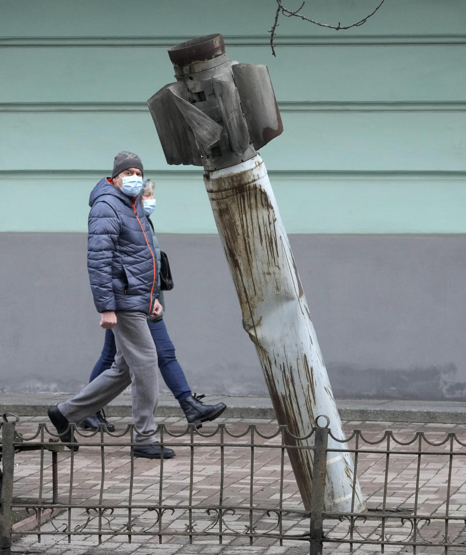 People pass by an unexploded missile fired by pro-Russian separatists in Ukraine's east and taken to Kyiv as a reminder of war, in Kyiv, Ukraine, Friday, Feb. 18, 2022. Russia has announced massive nuclear drills while Western leaders grasp for ways to avert a new war in Europe. Tensions are soaring after unusually dire U.S. warnings that Moscow could order an invasion of Ukraine any day. (AP Photo/Efrem Lukatsky)