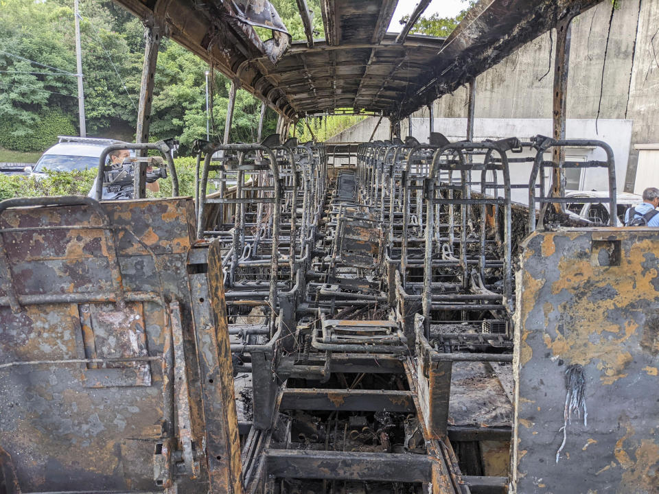 The burnt remains of a bus sits at a facility in Nagoya, Aichi prefecture, central Japan after being transferred from the site of an accident earlier in the day, Monday, Aug. 22, 2022. A passenger bus crashed into a dividing strip, overturned to its side and caught fire on an expressway in central Japan on Monday, leaving two people burned to death and slightly injuring seven others, police said. (Kyodo News via AP)