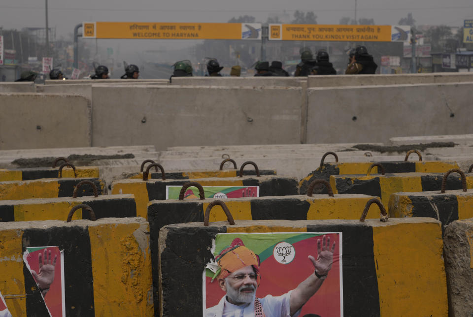 A Bharatiya Janata Party poster seeking a third term for Indian Prime Minister Narendra Modi is seen on a barricade erected by police to stop thousands of protesting farmers from entering the capital at Singhu near New Delhi India, Tuesday, Feb.13, 2024. Farmers, who began their march from northern Haryana and Punjab states, are asking for a guaranteed minimum support price for all farm produce. (AP Photo/Manish Swarup)
