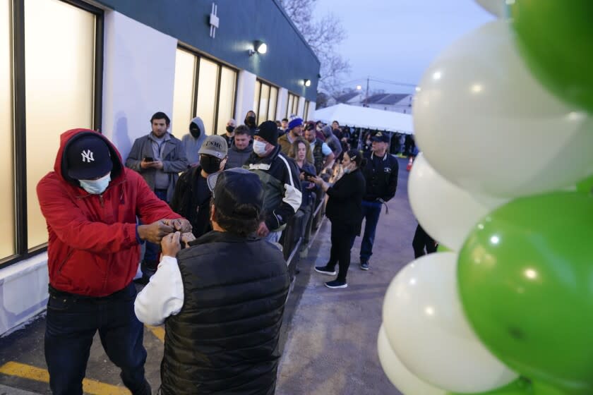People give fist bumps as they enter a RISE dispensary in Bloomfield, N.J., Thursday, April 21, 2022. Recreational sales of cannabis for adults 21 and older started Thursday, with the first alternative treatment centers opening at 6 a.m. in part of the state. (AP Photo/Seth Wenig)