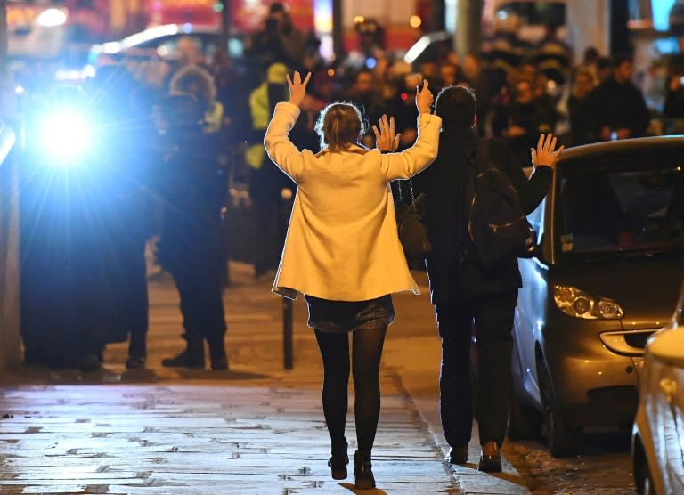 People hold their hands up as they walk towards police near the site of a shooting at the Champs Elysees in Paris