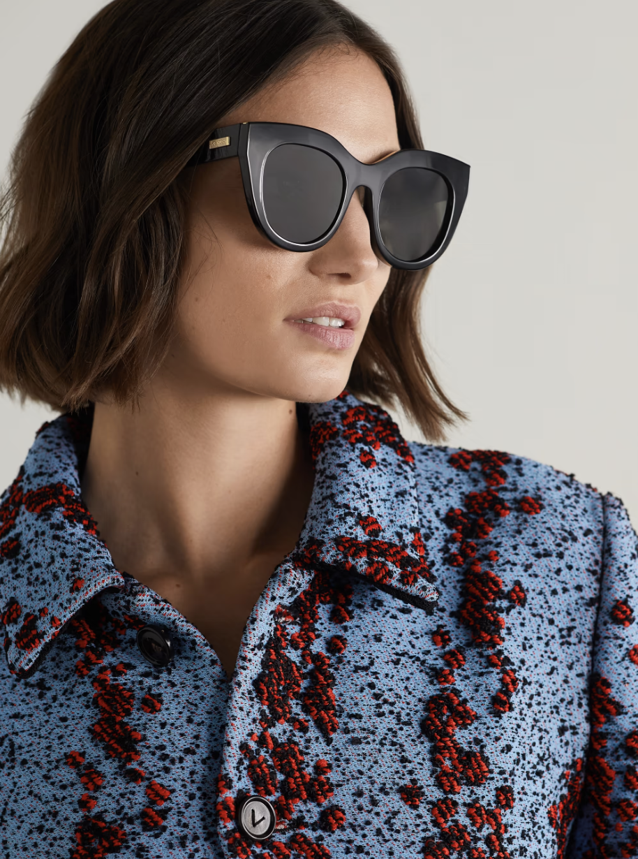 model wearing red and black sweater and black Le Specs Air Heart 51mm Cat Eye Sunglasses (photo via Net-A-Porter)