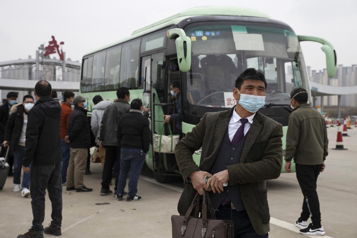 In this Thursday, April 2, 2020, photo, a man disembarks from a bus at an expressway gate at the border of Wuhan city in central China's Hubei province. Millions of Chinese workers are streaming back to factories, shops and offices, but many still face anti-coronavirus controls that add to their financial losses and aggravation. In Wuhan, police require a health check and documents from employers for returning workers.