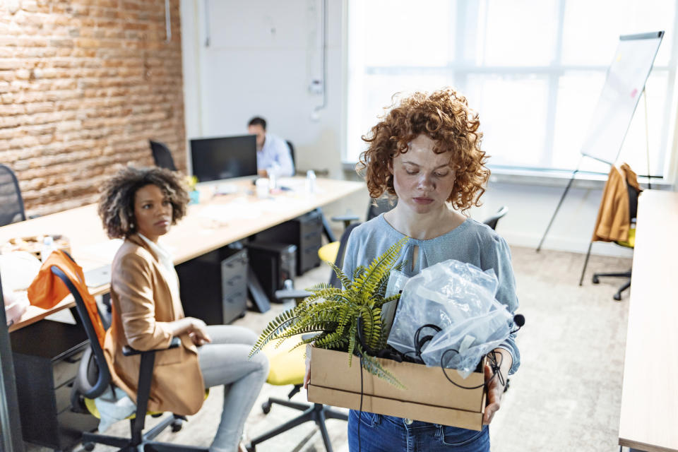 woman leaving an office with her belongings in a box