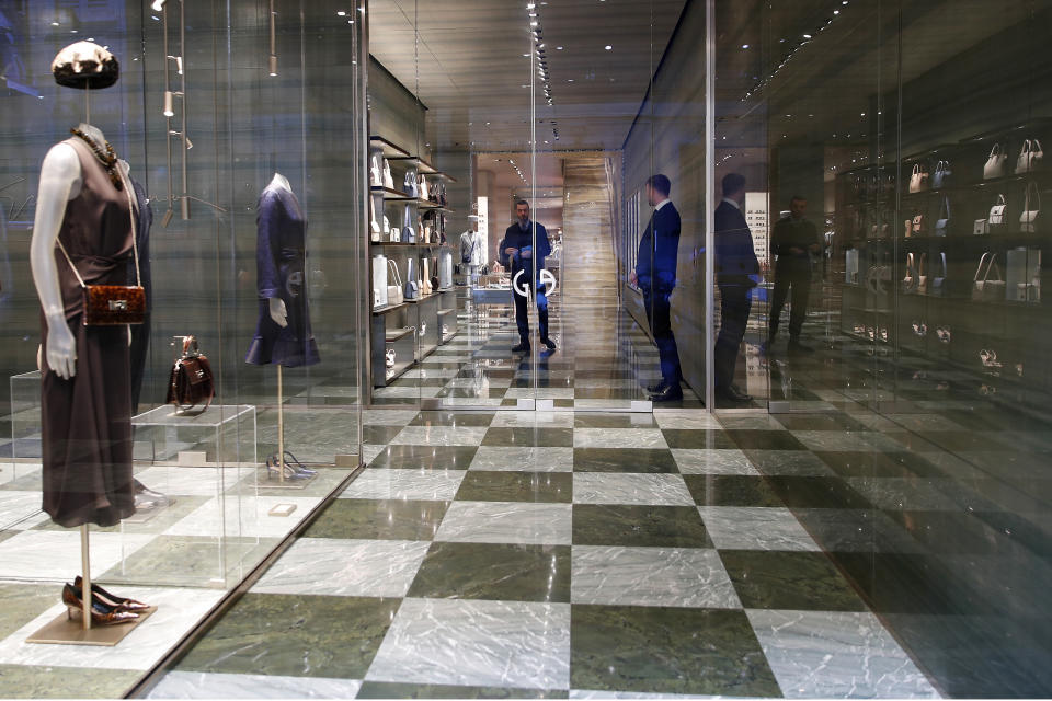 In this photo taken on Thursday, March 5, 2020, two shop assistants wait for customers at a fashion store in Monte Napoleone shopping street in Milan, Italy. With the coronavirus emergency deepening in Europe, Italy, a focal point in the contagion, risks falling back into recession as foreign tourists are spooked from visiting its cultural treasures and the global market shrinks for prized artisanal products, from fashion to design. (AP Photo/Antonio Calanni)