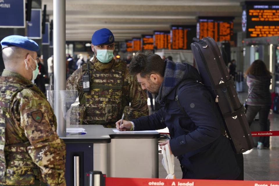 A traveler fills out a form at a check point set up by border police inside Rome's Termini train station, Tuesday, March 10, 2020. In Italy the government extended a coronavirus containment order previously limited to the country’s north to the rest of the country beginning Tuesday, with soldiers and police enforcing bans. (AP Photo/Andrew Medichini)