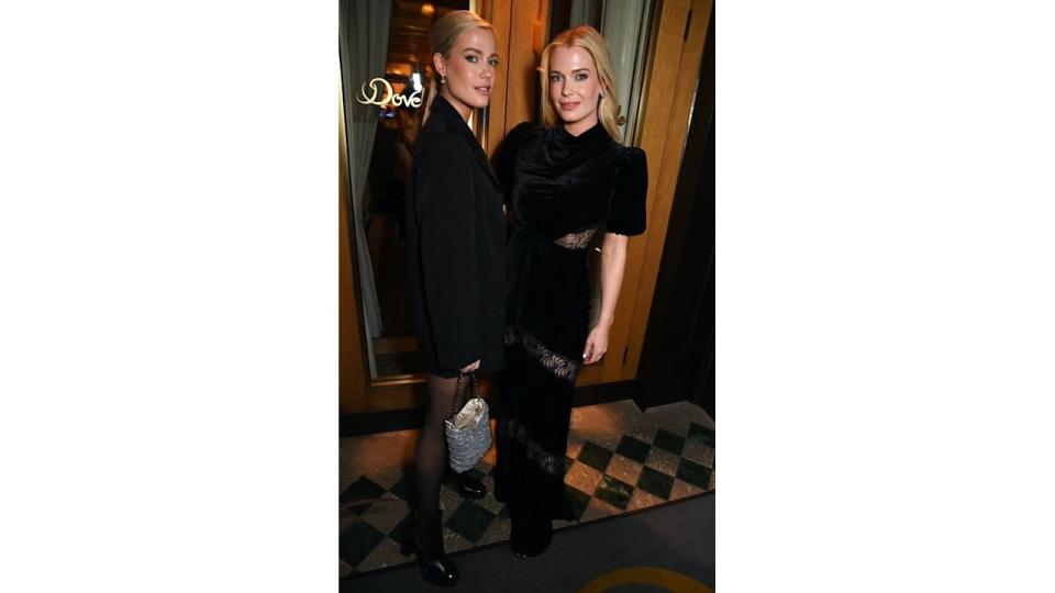 Lady Amelia Spencer and Lady Eliza Spencer  posing in glamorous outfits. One wears a black dress with lace accents, and the other wears a sleek black jacket and stockings, holding a sparkling handbag.