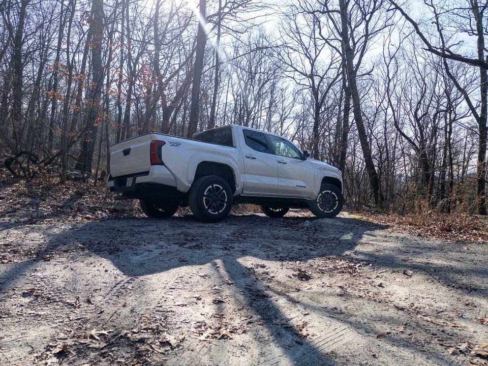 a white truck parked in a dirt road with trees on either side