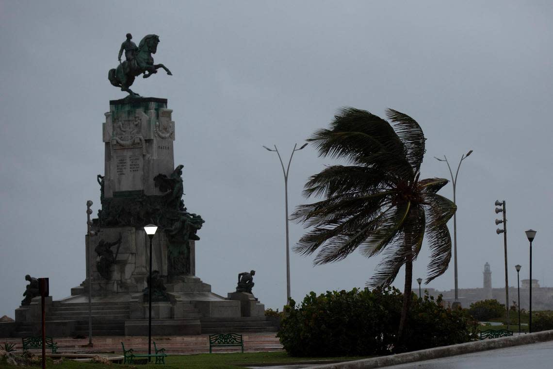 Wind blows a palm tree at the Antonio Maceo Monument along the malecon sea wall during the passing of Hurricane Ian in Havana, Cuba, early Thursday, Sept. 27, 2022.