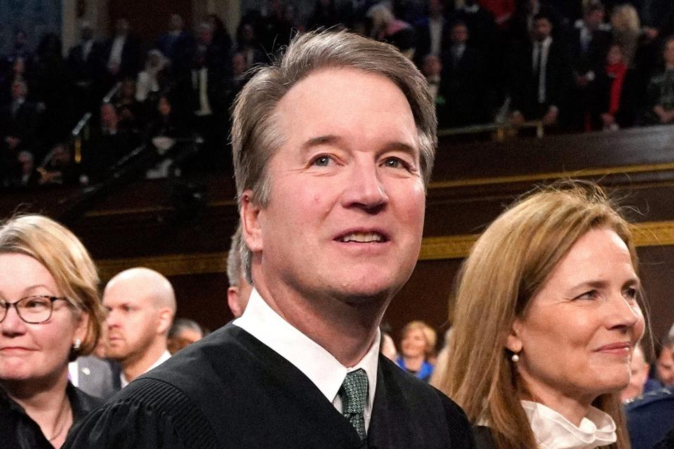 Brett Kavanaugh and Amy Coney Barrett wear Supreme Court robes and smile.