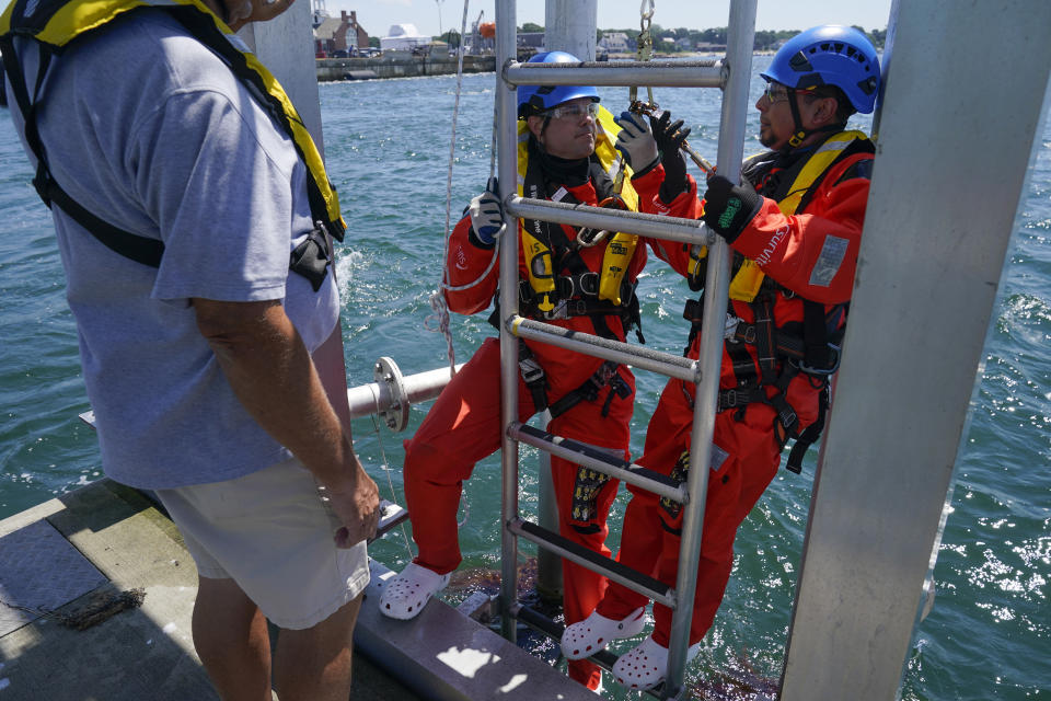 Tyler Spofford, left, and Sergio Cordova practice evacuation techniques on the water during a Global Wind Organisation certification class at the Massachusetts Maritime Academy in Bourne, Mass., Thursday, Aug. 4, 2022. At the 131-year-old maritime academy along Buzzards Bay, people who will build the nation's first commercial-scale offshore wind farm are learning the skills to stay safe while working around turbines at sea. (AP Photo/Seth Wenig)