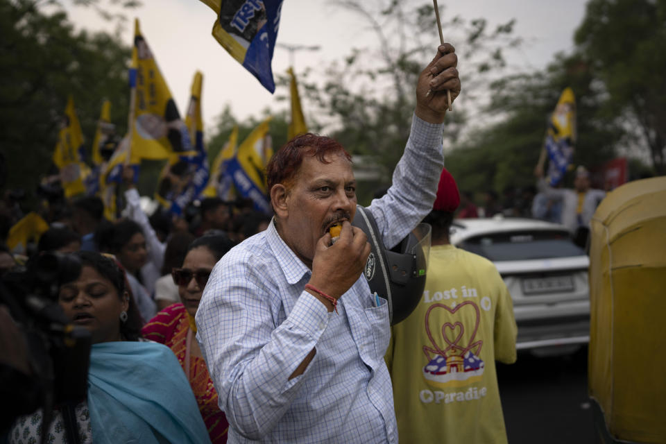 A supporter of the Aam Aadmi Party eats a sweet as he waits with others for the release of the party leader Arvind Kejriwal from Tihar Jail in New Delhi, India, Friday, May 10, 2024. The Supreme Court ordered Arvind Kejriwal's temporary release enabling him to campaign in the country's national election until the voting ends on June 1. (AP Photo/Altaf Qadri)
