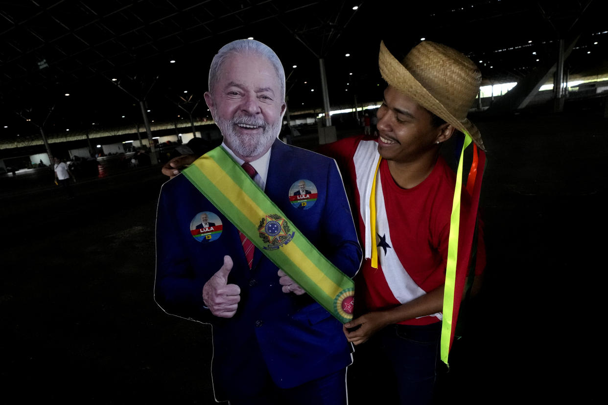 Leonam Costa places a replica of the presidential sash on a puppet of Brazilian President-elect Luiz Inacio Lula da Silva, in a camp of supporters of the president-elect, in Brasilia, Brazil, Saturday, Dec. 31, 2022. Lula defeated far-right President Jair Bolsonaro in the Oct. 30 run-off vote by less than 2 percentage points. (AP Photo/Eraldo Peres)