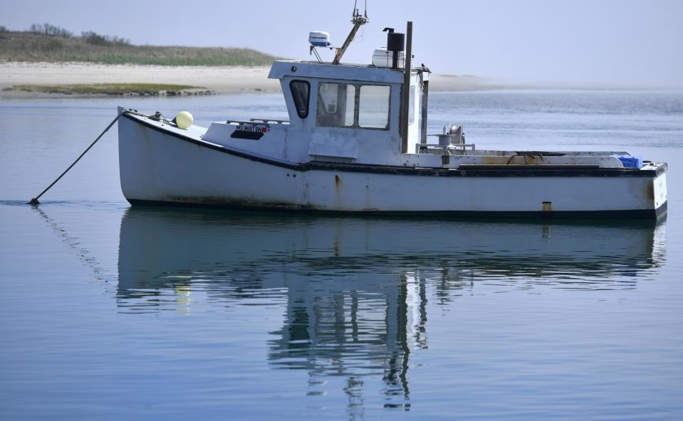 A fishing boat waits on its mooring just off the Chatham Fish Pier as a fog bank finally begins to burn off at mid-day to the east in this April 28, 2023 Cape Cod Times file photo.