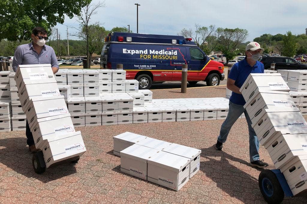 FILE - In this May 1, 2020, file photo, campaign workers David Woodruff, left, and Jason White, right, deliver boxes of initiative petitions signatures to the Missouri secretary of state's office in Jefferson City, Mo. President Donald Trump is still trying to overturn "Obamacare," but his predecessor's health care law keeps gaining ground in places where it was once unwelcome. Missouri voters this week approved Medicaid expansion by a 53% to 47% margin, making the conservative state the seventh to do so under Trump.