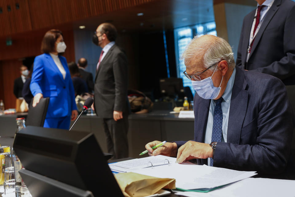 European Union foreign policy chief Josep Borrell looks at his papers as Belarusian opposition politician Sviatlana Tsikhanouskaya, background left, talks to Cypriot Foreign Minister Nicos Christodoulides during a European Foreign Affairs Ministers meeting at the European Council building in Luxembourg, Monday, June 21, 2021. EU foreign ministers were set to approve Monday a new set of sanctions against scores of officials in Belarus and prepare a series of measures aimed at the country's economy. (Johanna Geron/Pool Photo via AP)