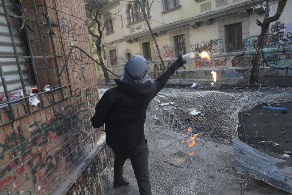 An anti-government demonstrator throws a petrol bomb at the police during clashes in Santiago, Chile, Tuesday, Nov. 19, 2019. Chile has been facing weeks of unrest, triggered by a relatively minor increase in subway fares. The protests have shaken a nation noted for economic stability over the past decades, which has seen steadily declining poverty despite persistent high rates of inequality. (AP Photo/Esteban Felix)