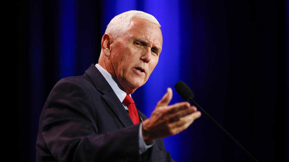 Former Vice President Mike Pence stands at a microphone as he gives a speech.