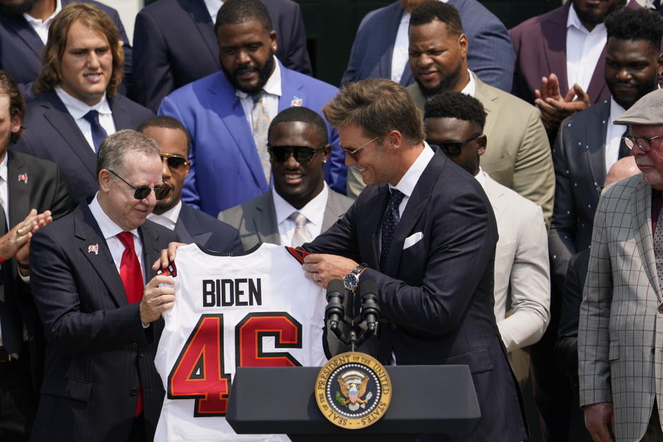 Tampa Bay Buccaneers quarterback Tom Brady and Tampa Bay Buccaneers co-owner Bryan Glazer, left, hold a jersey for President Joe Biden during a ceremony on the South Lawn of the White House, in Washington, Tuesday, July 20, 2021, the president honored the Super Bowl Champion Tampa Bay Buccaneers for their Super Bowl LV victory. (AP Photo/Andrew Harnik)