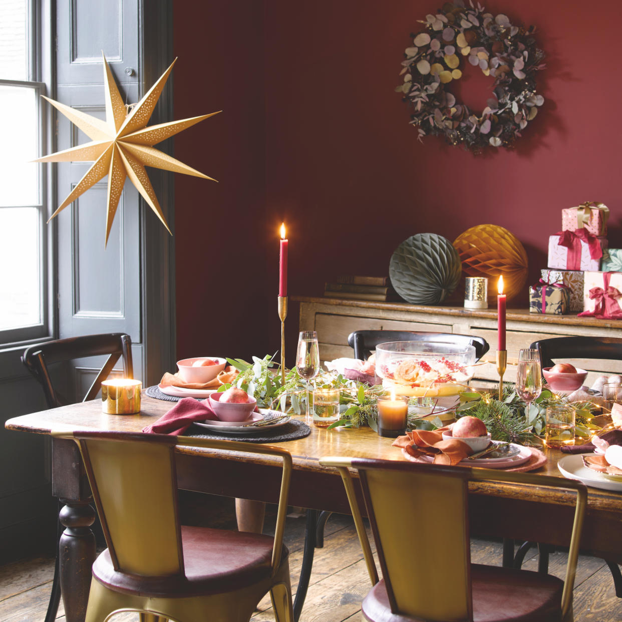  Christmas dining table with red wall and wreath. 