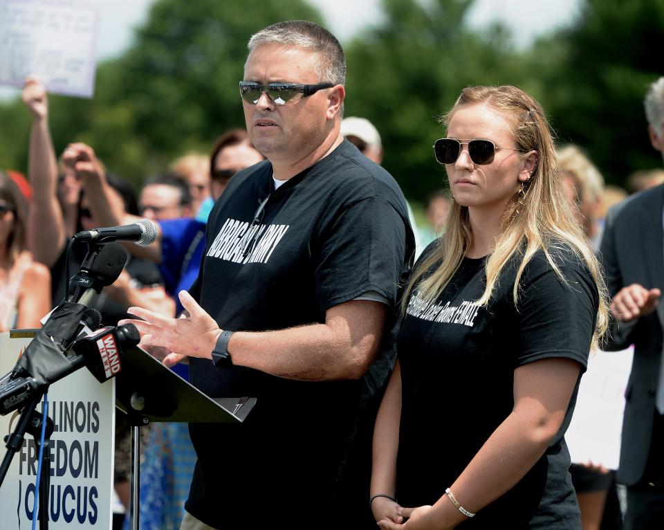 Dan Wheeler and his daughter, Abbigail, speak at a rally put on by the Illinois Freedom Caucus and the Independent Women's Forum at Rotary Park Thursday, July 13, 2023.