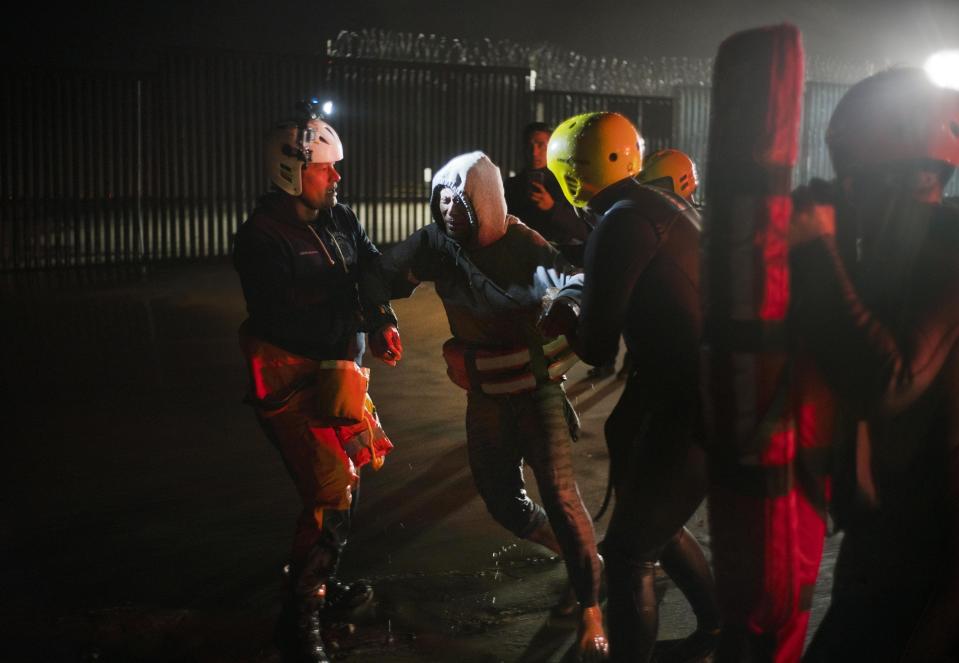 Authorities hold a Honduran migrant who was rescued from the water as he tried to cross the U.S. border by the sea in Tijuana beach, Mexico, Thursday, Nov. 29, 2018. Aid workers and humanitarian organizations expressed concerns Thursday about the unsanitary conditions at the sports complex in Tijuana where more than 6,000 Central American migrants are packed into a space adequate for half that many people and where lice infestations and respiratory infections are rampant. (AP Photo/Ramon Espinosa)