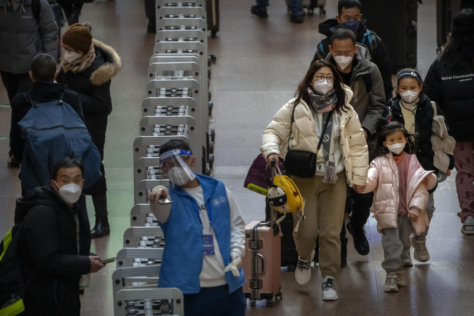 A family carrying their luggage walks along a concourse at Beijing West Railway Station in Beijing, Wednesday, Jan. 18, 2023. A population that has crested and is slowly shrinking will pose new challenges for China's leaders, ranging from encouraging young people to start families, to persuading seniors to stay in the workforce longer and parents to allow their children to join the military. (AP Photo/Mark Schiefelbein)