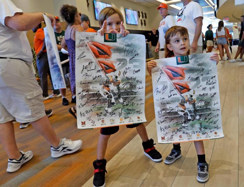 Canes fans Jackson Chida, 8, and Kane Green, 4, hold up posters autographed by Miami Hurricanes players during the University of Miami’s annual CanesFest at Hard Rock Stadium in Miami Gardens on Saturday, August 12, 2023.