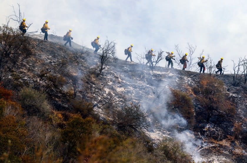 Los Angeles, CALIFORNIA—MAY 16, 2021—Firefighters work the fire line in canyons between Pacific Palisades and Topanga Canyon as air drops continued non-stop throughout the day on Sunday May 16, 2021. (Carolyn Cole / Los Angeles Times)