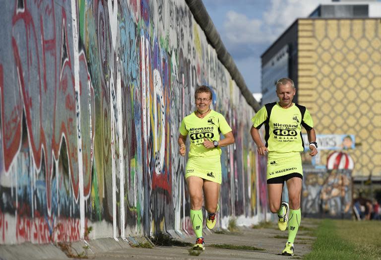 Martina Schliep and her partner Gaston Pruefer run along the old Berlin Wall on August 11, 2014 as they train before taking part in the "100MeilenBerlin" marathon event