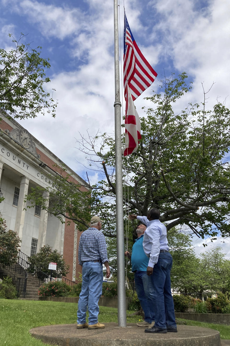 Men lower the U.S. and Alabama flag to half-staff at the Tallapoosa County Courthouse in Dadeville, Ala., on Sunday, April 16, 2023, hours after a fatal shooting less than a block away. Several were killed during a shooting at a birthday party Saturday night, the Alabama Law Enforcement Agency said. (AP Photo/Jeff Amy)
