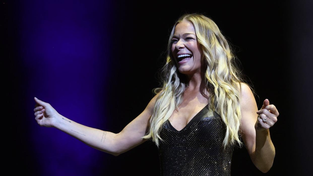 leann rimes smiling on stage in a black outfit