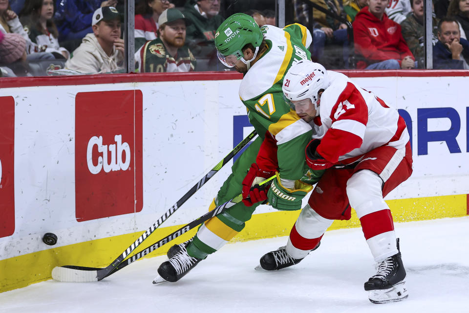 Minnesota Wild left wing Marcus Foligno (17) and Detroit Red Wings center Austin Czarnik (21) compete for the puck during the second period of an NHL hockey game Wednesday, Dec. 27, 2023, in St. Paul, Minn. (AP Photo/Matt Krohn)