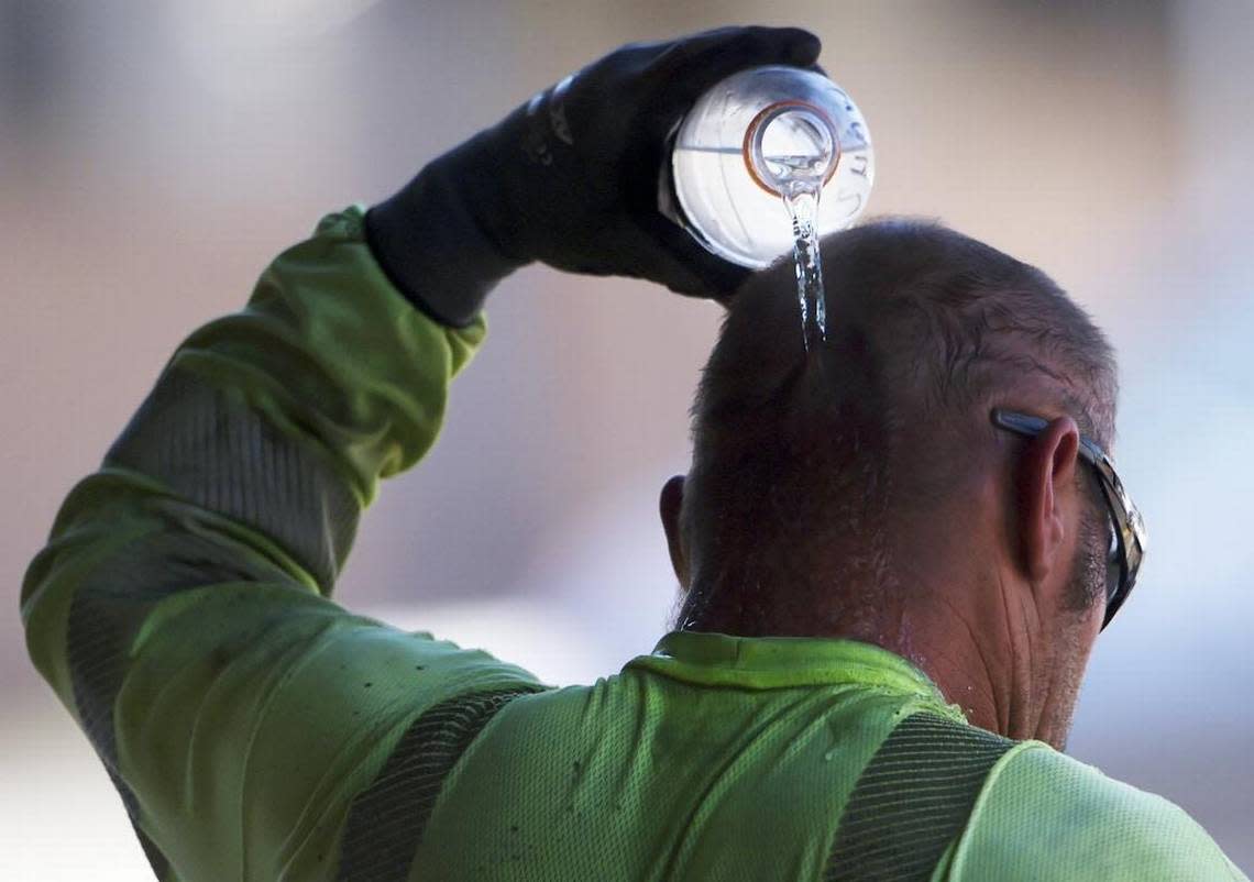 A construction worker pours a bottle of water over his head as he cools off in the shade at the end of the work day Wednesday, June 21, 2017 in Fresno.