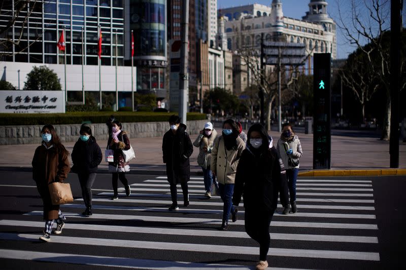 Pedestrians wearing face masks cross a road, as the country is hit by an outbreak of the novel coronavirus, in Shanghai