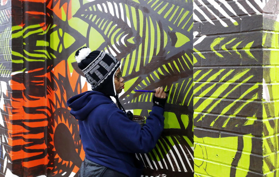 In this Dec. 14, 2018, photo, Shanequa Gay paints mural on a MARTA station wall near the Mercedes Benz Stadium in Atlanta. A series of about 30 murals on walls around the downtown Atlanta stadium that will host the Super Bowl aims to highlight Atlanta's civil rights legacy. The murals are part of an initiative called "Off The Wall: Atlanta's Civil Rights and Social Justice Journey." (AP Photo/John Bazemore)