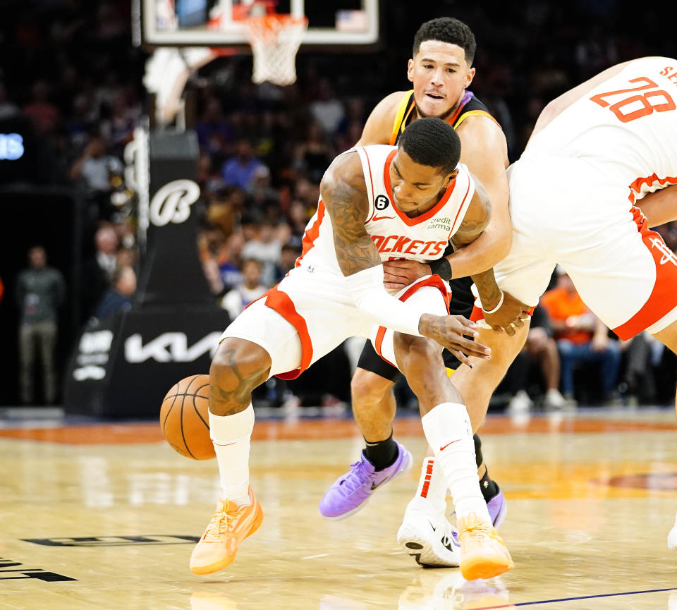 Phoenix Suns' Devin Booker, top, knocks the ball away from Houston Rockets' Kevin Porter Jr., bottom, during the first half of an NBA basketball game, Sunday, Oct. 30, 2022, in Phoenix. (AP Photo/Darryl Webb)