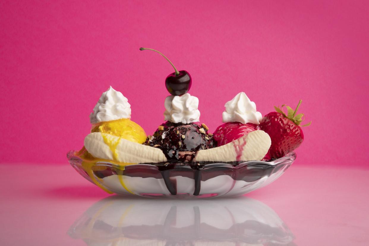 A banana split on a vibrant pink background.