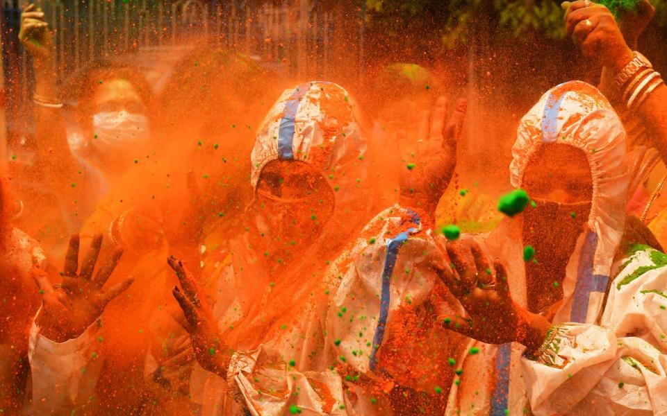 People wearing protective suits as a preventive measure play with coloured powders as they celebrate Holi, the spring festival of colours - Dibyangshu SARKAR / AFP