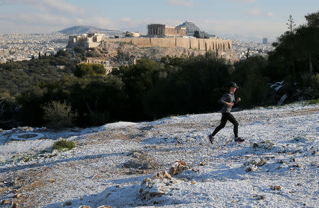 A man jogs on snow-covered Filopappou Hill opposite the Acropolis archaeological site, following a snowfall in Athens, Greece, January 8, 2019. REUTERS/Costas Baltas