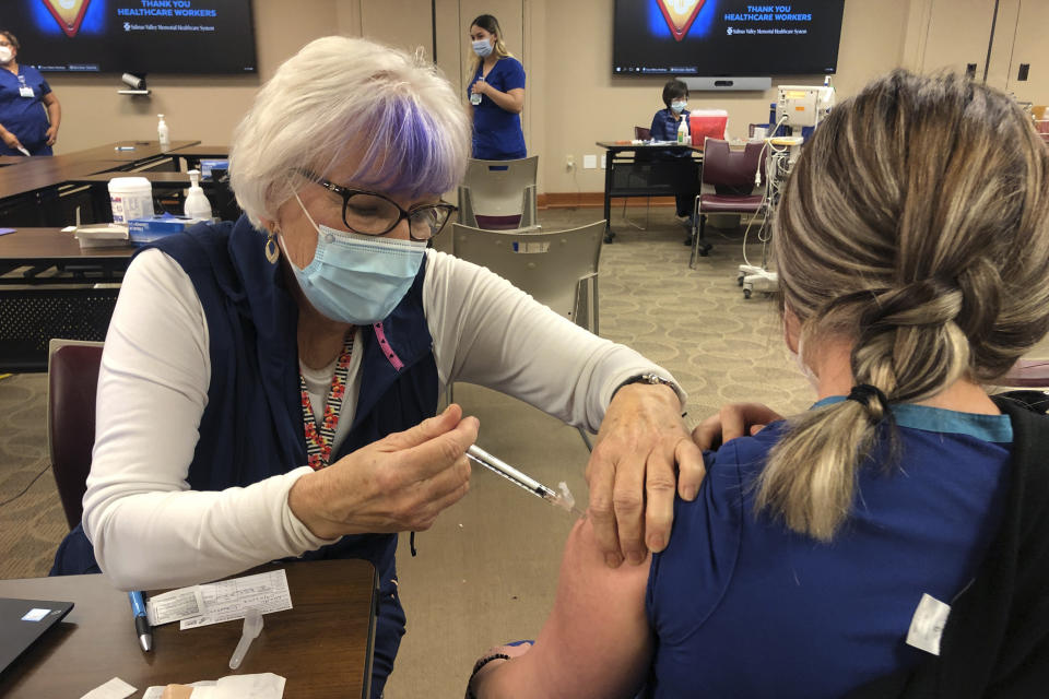 Nurse practitioner Sigrid Stokes, 76, gives a health care worker a COVID-19 vaccine at the Salinas Valley Memorial Hospital in Salinas, Calif., Wednesday, Feb. 3, 2021. Stokes is following in her family's footsteps during the pandemic. In 1918, Stokes' mother Kristine Berg Mueller was a 14-year-old hospital volunteer in Norway during the Spanish Flu pandemic, putting her in regular contact with the deadly disease. (AP Photo/Haven Daley)