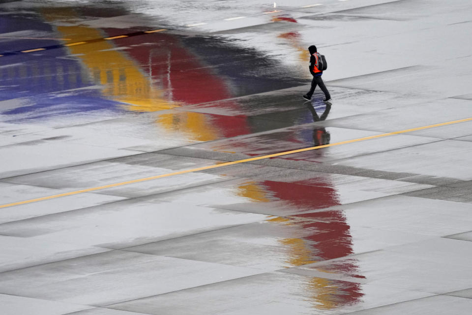 FILE - A ground operations crew member walks past a Southwest Airlines jet sitting at a gate, Dec. 28, 2022, at Sky Harbor International Airport in Phoenix. With its flights now running on a roughly normal schedule, Southwest Airlines is turning its attention to luring back customers and repairing damage to a reputation for service after canceling 15,000 flights around Christmas. The disruptions started with a winter storm and snowballed when Southwest's ancient crew-scheduling technology failed.(AP Photo/Matt York, File)