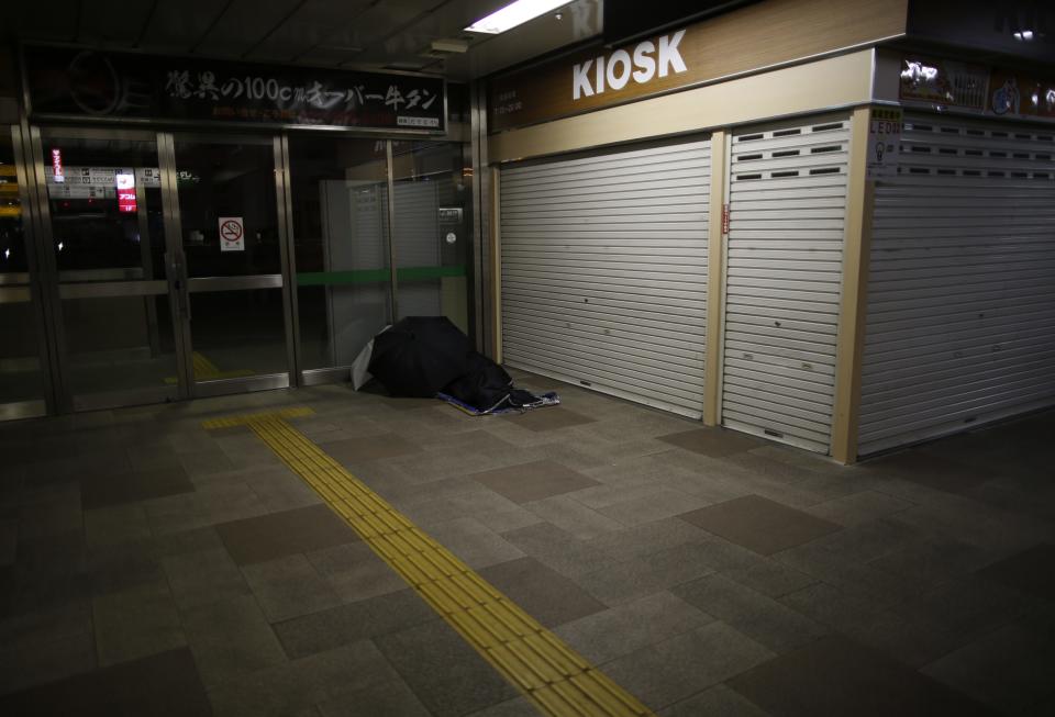 A homeless man rests on the ground at a concourse of Sendai Station in Sendai, northern Japan