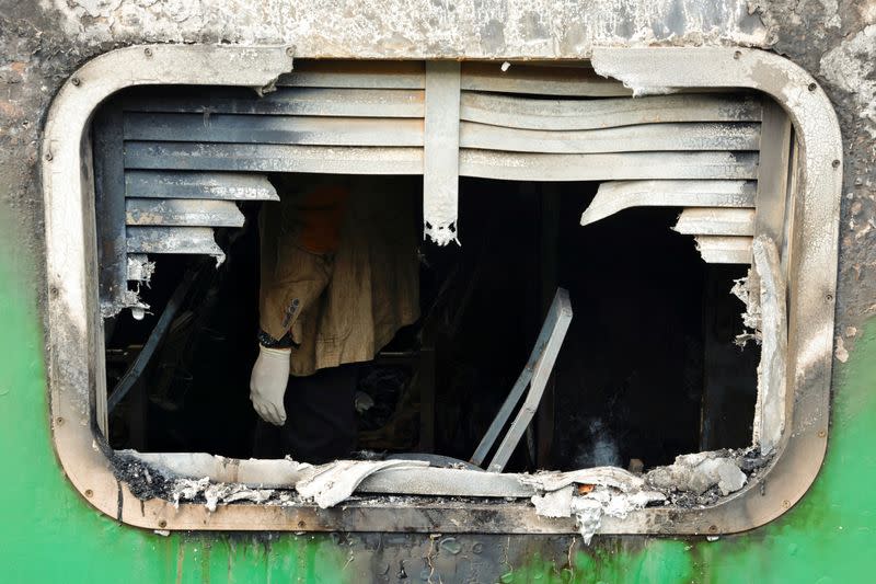 Crime Scene Unit members inspect the passenger train that was set on fire during a countrywide strike called by the Bangladesh Nationalist Party, in Dhaka