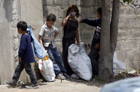 Syrian refugee children collect plastics as they stand along a street in south of Sidon, southern Lebanon June 10, 2014. REUTERS/Ali Hashisho