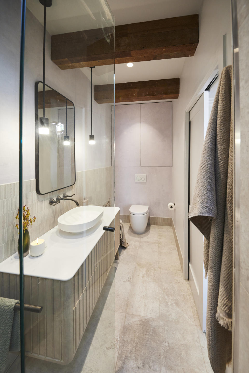 A wide shot of the bathroom, vanity on the left, toilet at the back. 