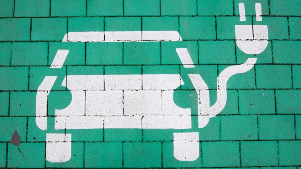 Ein Parkplatz mit einer Ladesäule für Elektroautos ist grün markiert.